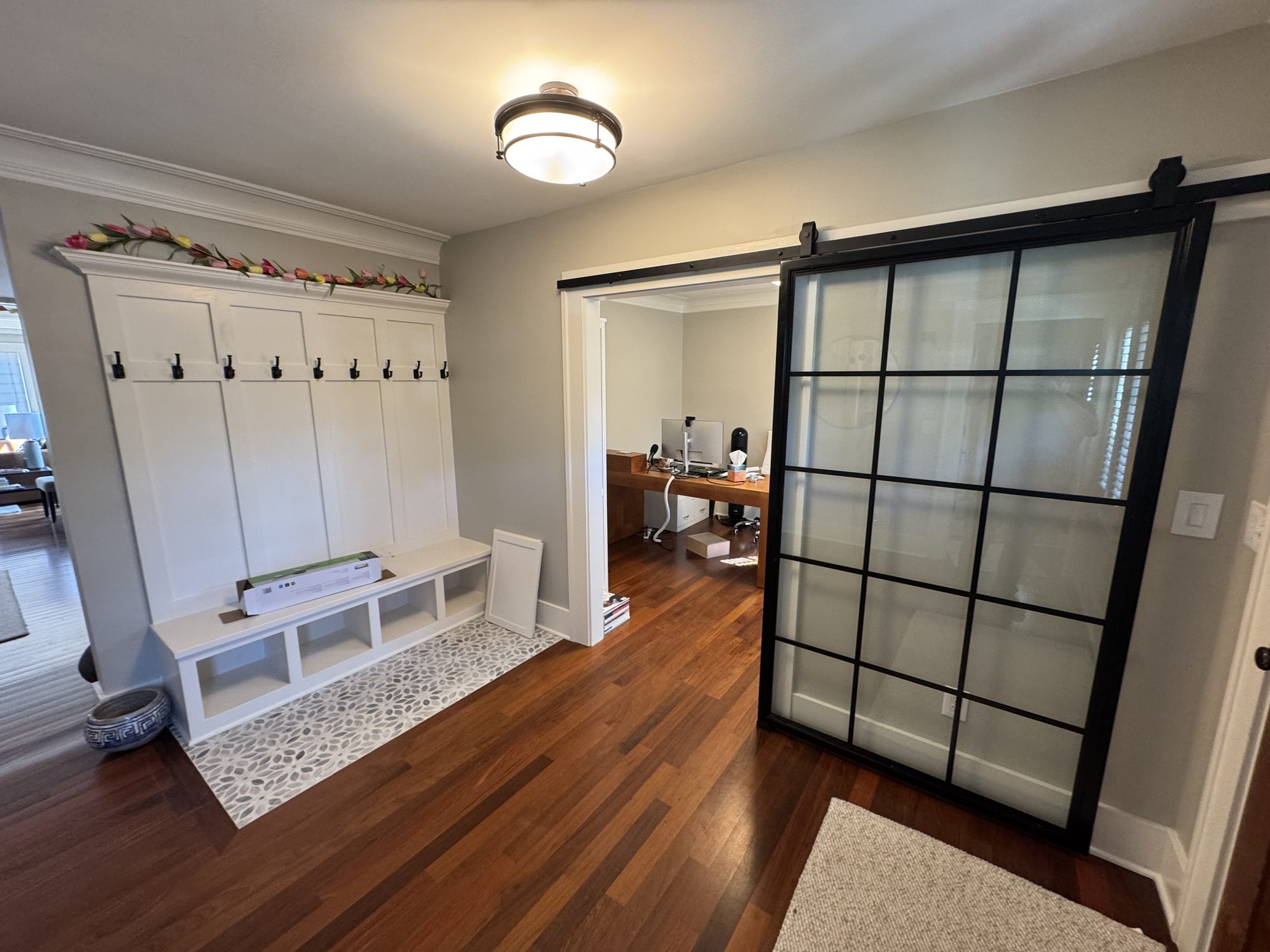 Custom mudroom with built-in bench, hooks, and steel-framed sliding door