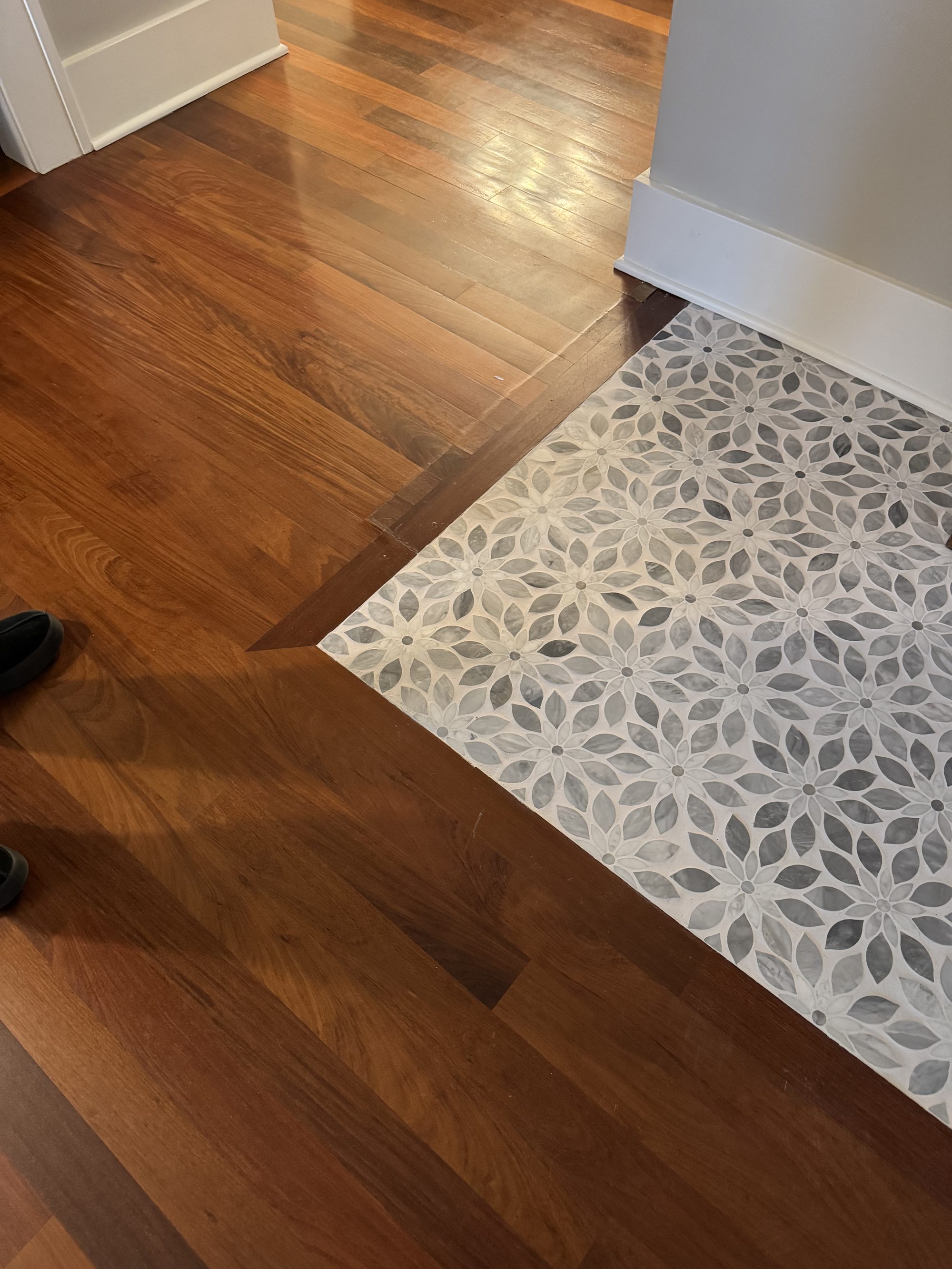 Mosaic tile entryway inset into hardwood in a restored home