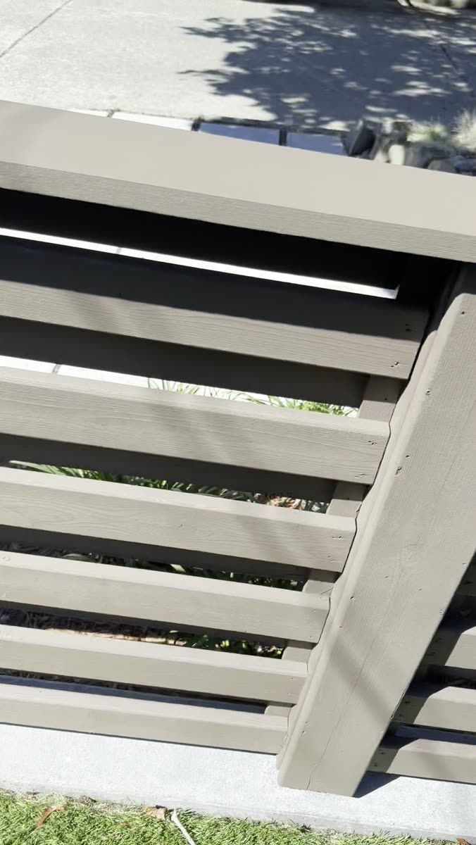 Horizontal slat fence part way through being re-stained